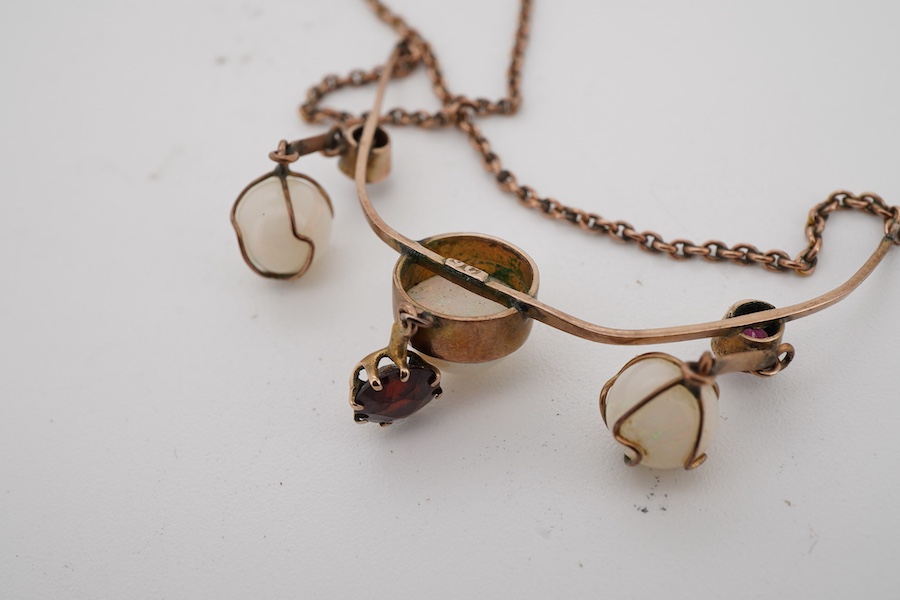 An early 20th century yellow metal, thee stone white opal and three stone garnet set drop necklace, approximately 44cm.